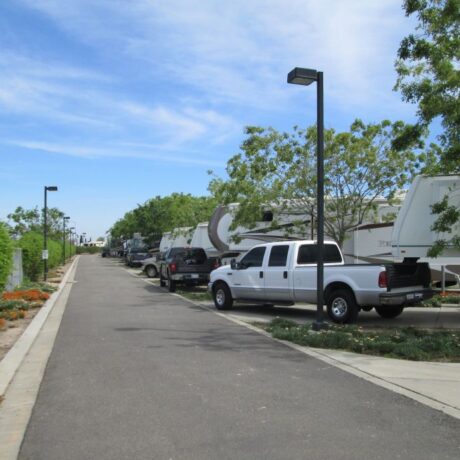 A row of large RVs parked on wide, paved sites at Flag City RV Resort in Lodi, CA.