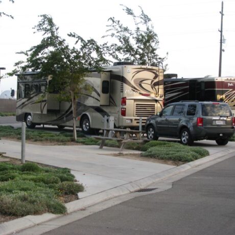 A row of large RVs parked on wide, paved sites at Flag City RV Resort in Lodi, CA.