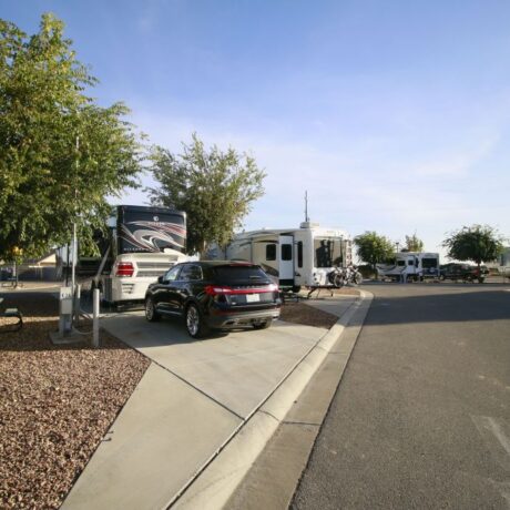 A row of large RVs parked on wide, paved sites at Flag City RV Resort in Lodi, CA.