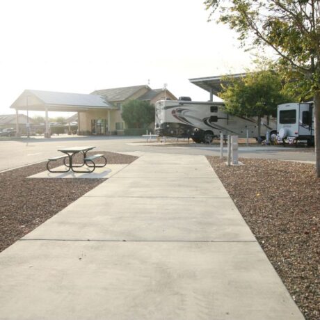 A row of large RVs parked on wide, paved sites at Flag City RV Resort in Lodi, CA.