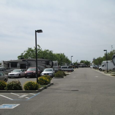 A row of large RVs parked on wide, paved sites at Flag City RV Resort in Lodi, CA.