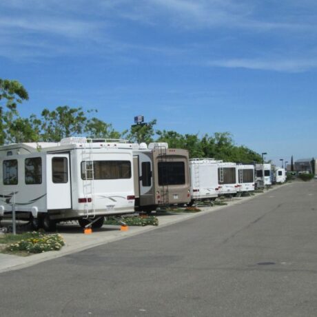 A row of large RVs parked on wide, paved sites at Flag City RV Resort in Lodi, CA.